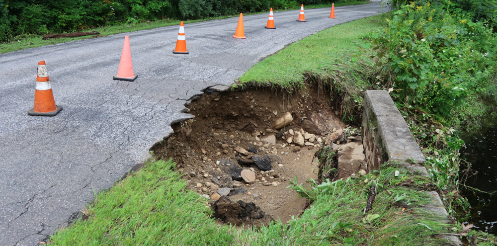 Wall of water damages road in Warren